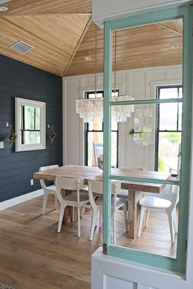 farmhouse dining room, navy blue wall, shiplap, chandelier, wood dining table, west elm, wall vase, white mirror, board and batten, white dining chairs