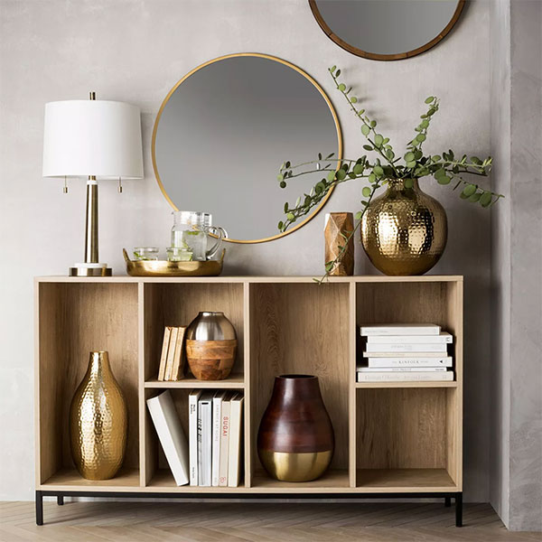 gold brass round mirror on beige wall above console table with lamp