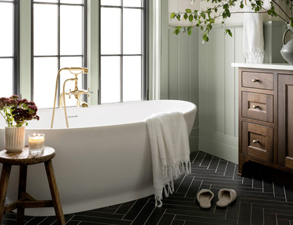 grey-green modern farmhouse bathroom with freestanding bathtub and black limestone herringbone tile floor and dark wood bath vanity