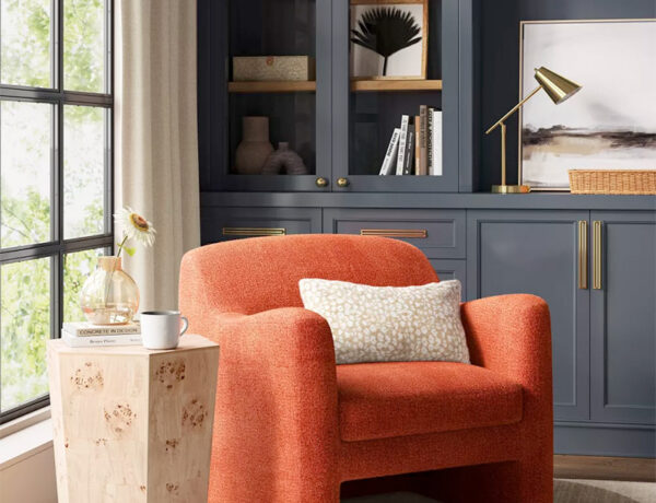 burnt orange modern accent chair next to a hexagon burle wood side table in front of charcoal grey built-in cabinets